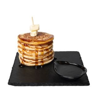 Pila di pancakes con burro, sciroppo d'acero e zucchero a velo