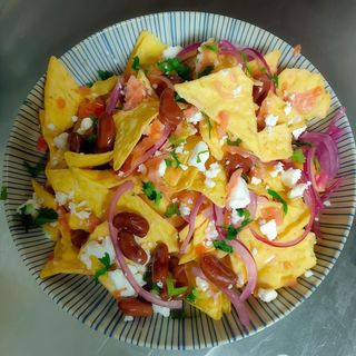 Totopos con tomate, frijoles, queso feta y cebolla cítrica