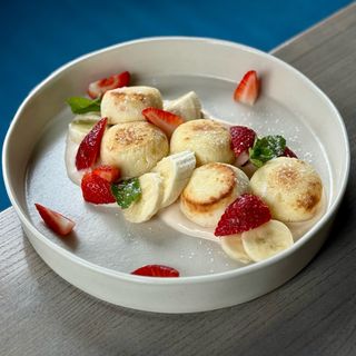 Домашні сирники з соусом з пряженої сметани, свіжими ягодами та бананом