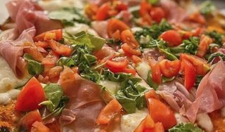 Pizza tonda rossa con mozzarella, rucola, pomodorini, crudo e burratina