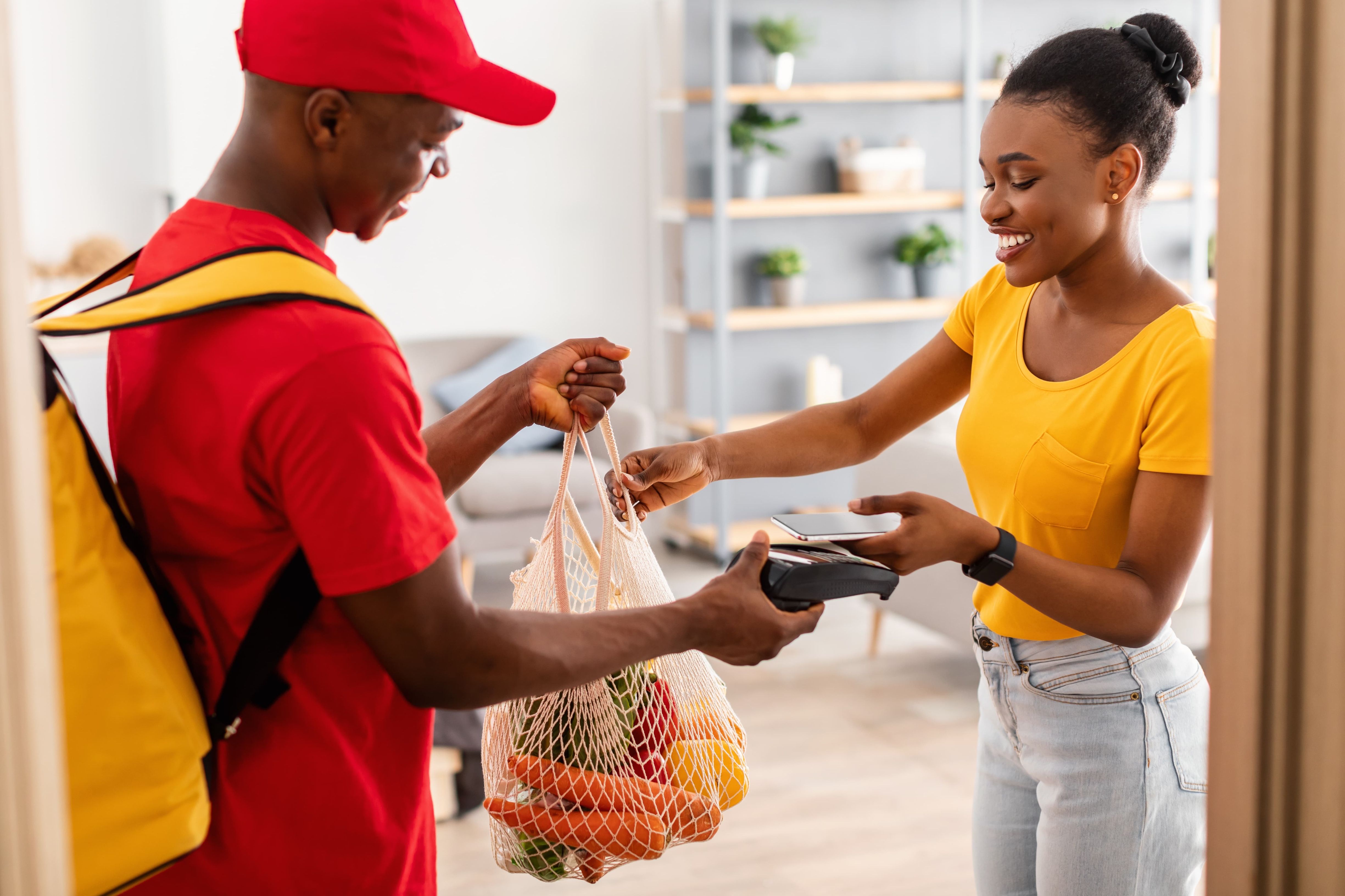 Man hands grocery delivery to woman at door