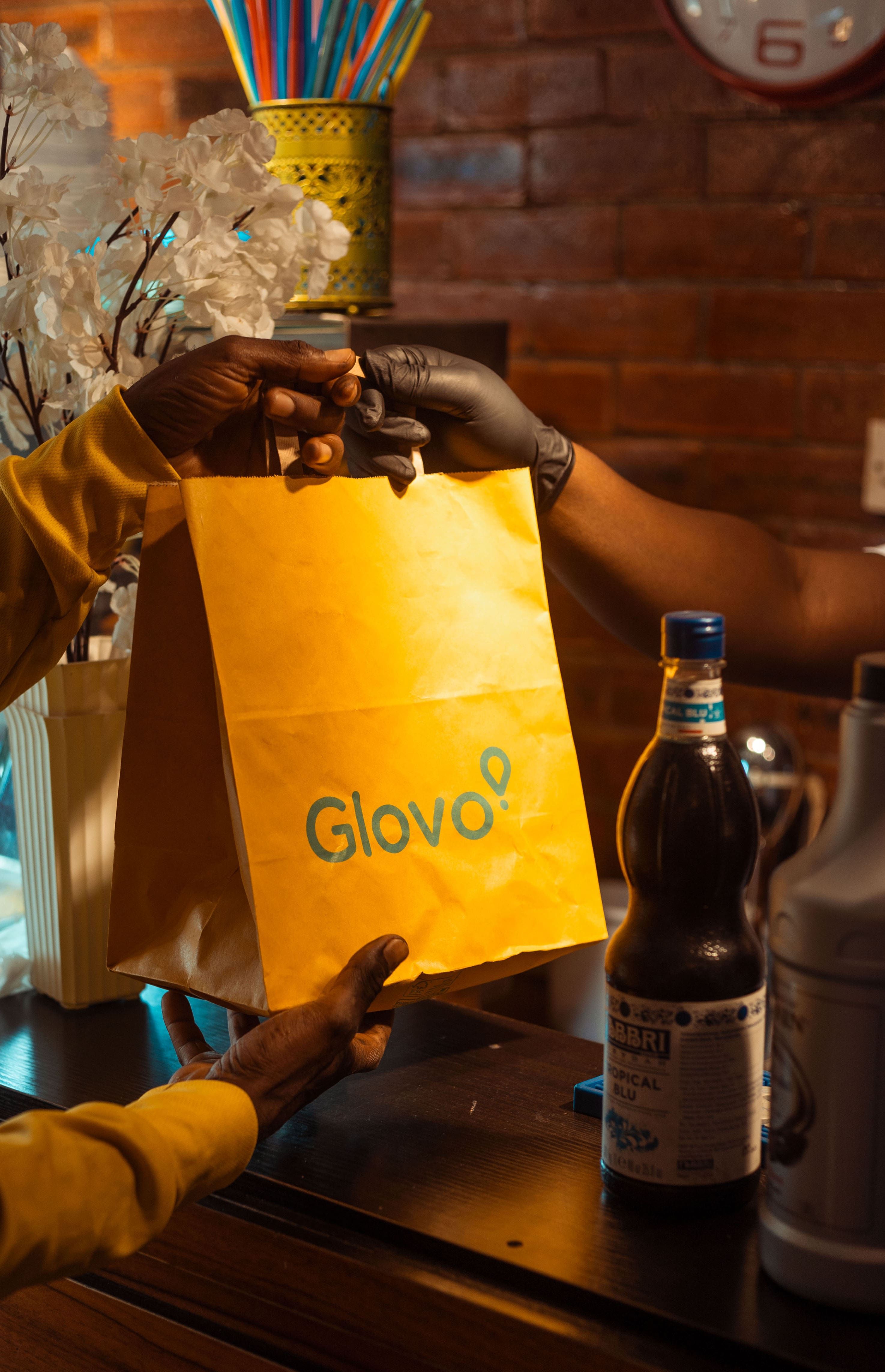 A customer is handed their order in a Glovo bag